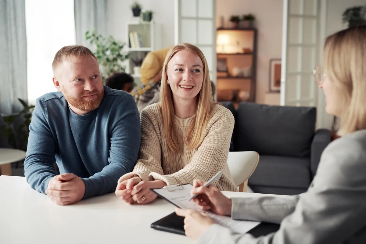 Smiling couple meeting an adviser at a desk in a bright modern office