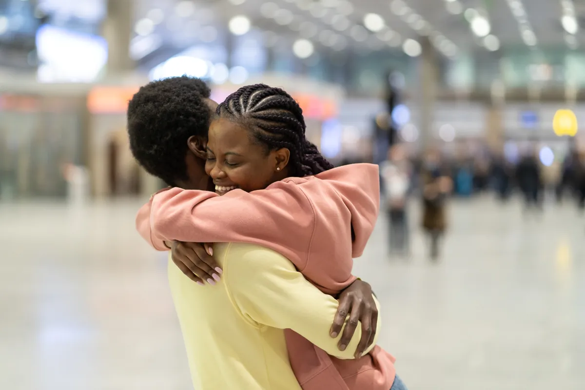 Couple sharing a joyful hug in a bright airport arrivals hall