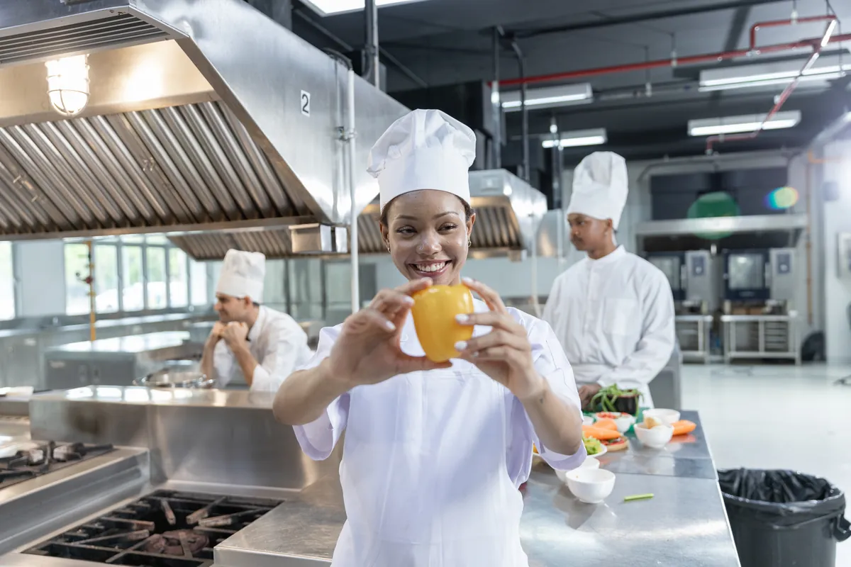 Smiling chef in a bright stainless steel commercial kitchen