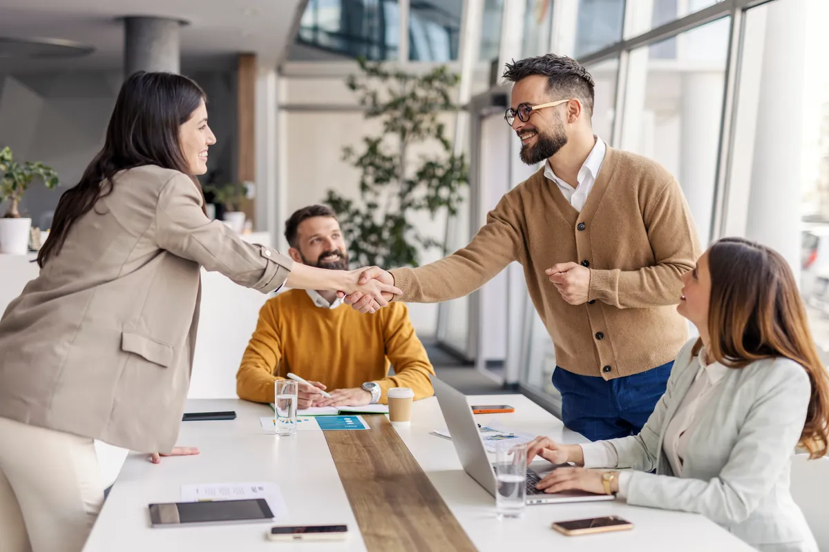 Multicultural team shaking hands around a table in a bright office