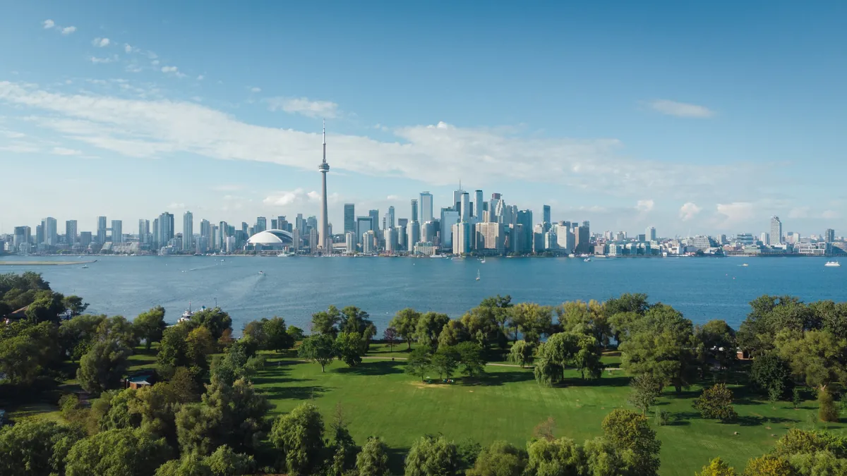 Toronto skyline and CN Tower across Lake Ontario from a green island park