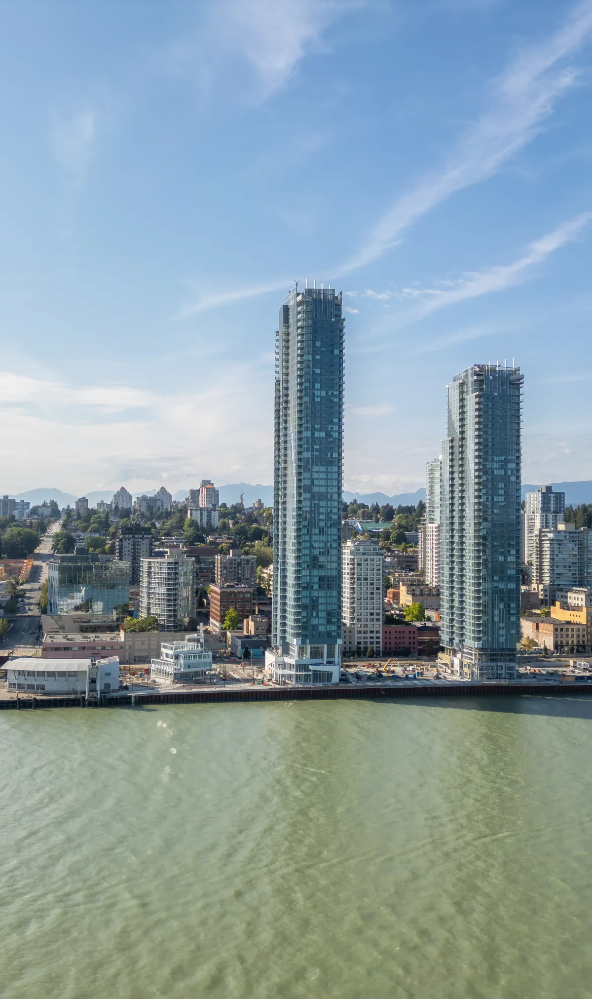 Vancouver waterfront towers above calm water under a blue sky